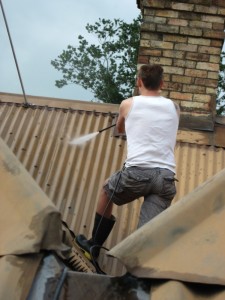 Andrew J. Wharton washing roof of villa in Whakatete Bay, New Zealand
